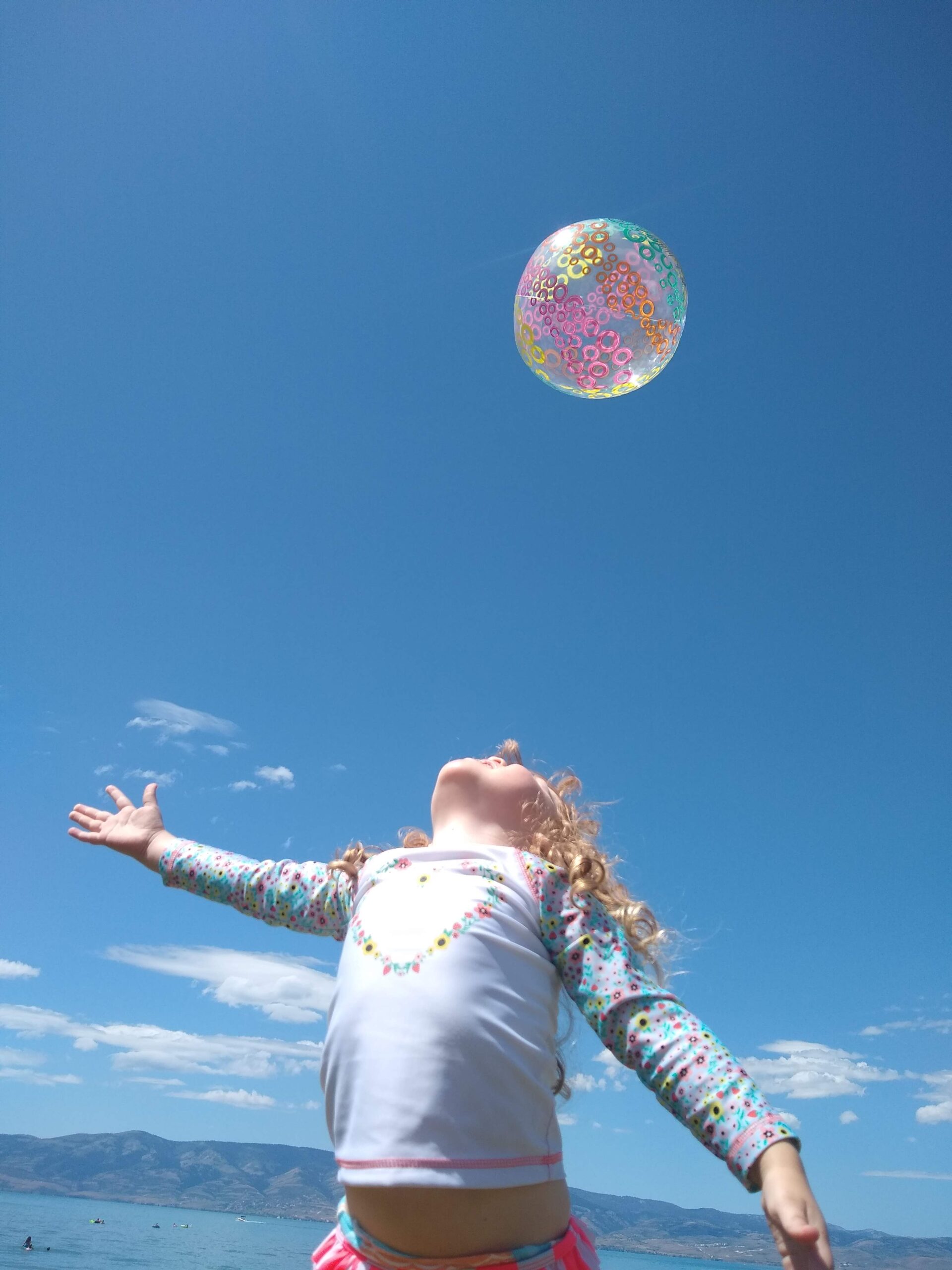 Little girl throwing a beach ball in the air.