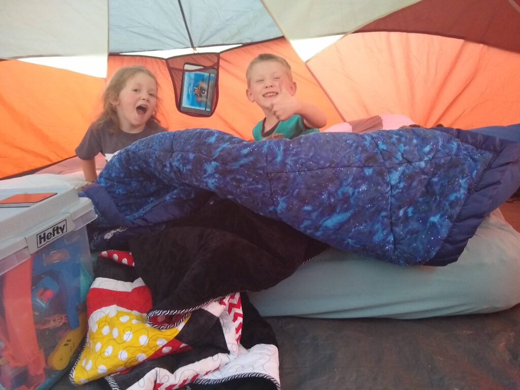 My son and daughter in our tent with toys, blankets, and an air mattress ready for backyard camping