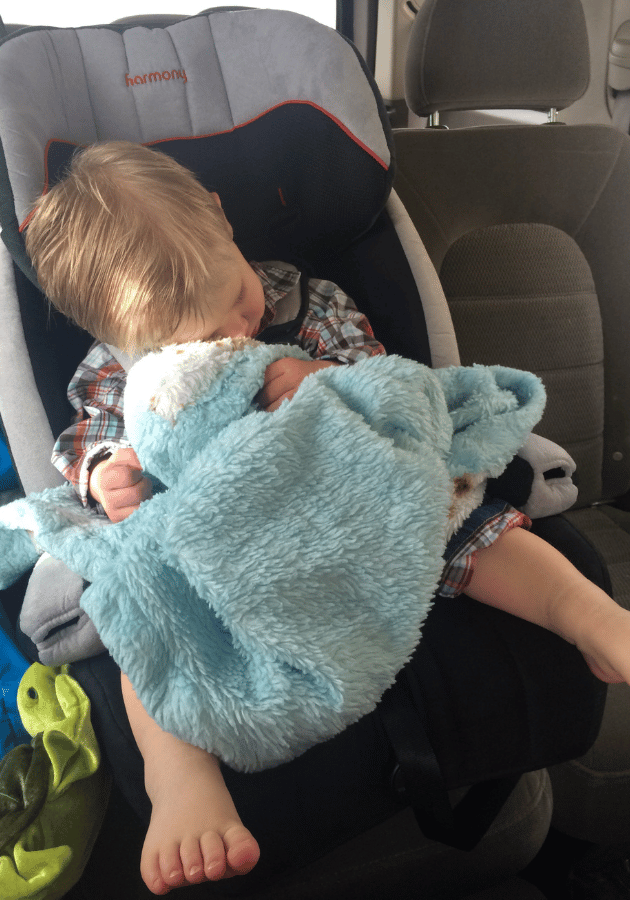 My son sleeping with his blanket and stuffed animal on a road trip