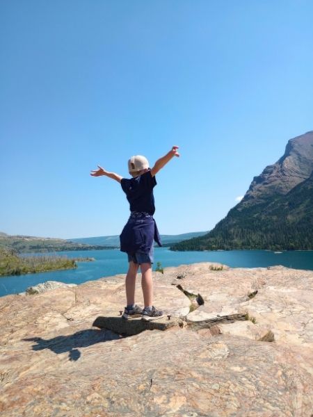 My son with his arms outstretched over looking Saint Mary Lake from the Sun Point Nature Trail in Glacier National Park