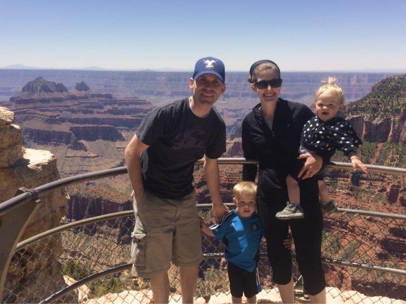 My husband, me, our three year old son and one year old daughter standing in front of a vista of the Grand Canyon.