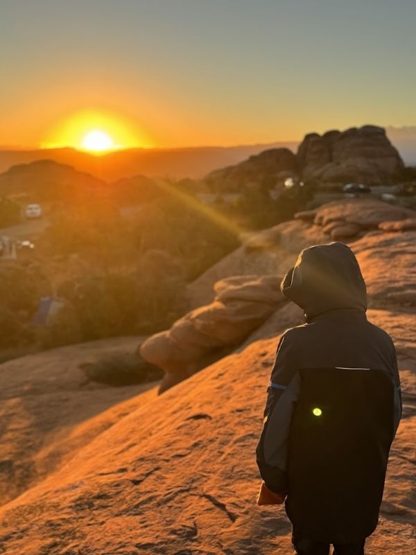 My son looking at the sunrise in Arches National Park from Devils Garden Campground