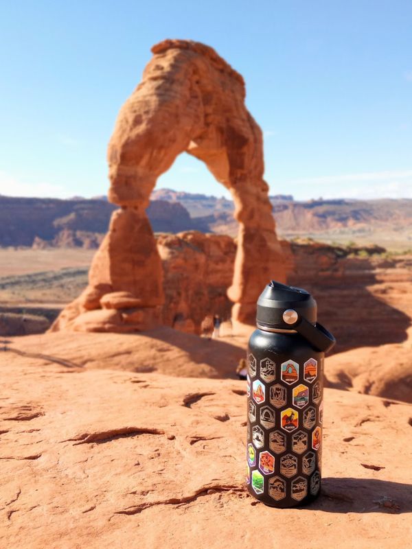 My black metal water bottle with national park stickers with Delicate Arch in the background